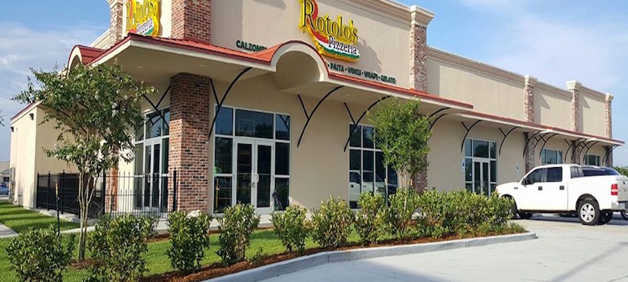 Rotolo's Pizzeria features brick and beige walls, large windows, and a white pickup truck outside—come in for handcrafted pizza!.