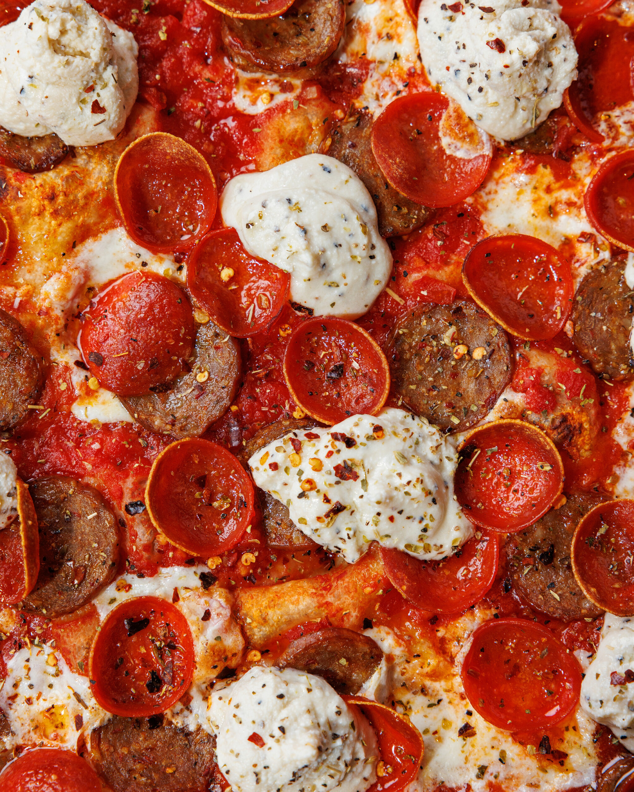Close-up of a Rotolo's Craft & Crust pizza topped with pepperoni, sausage, tomato sauce, cheese, and seasoned ricotta.