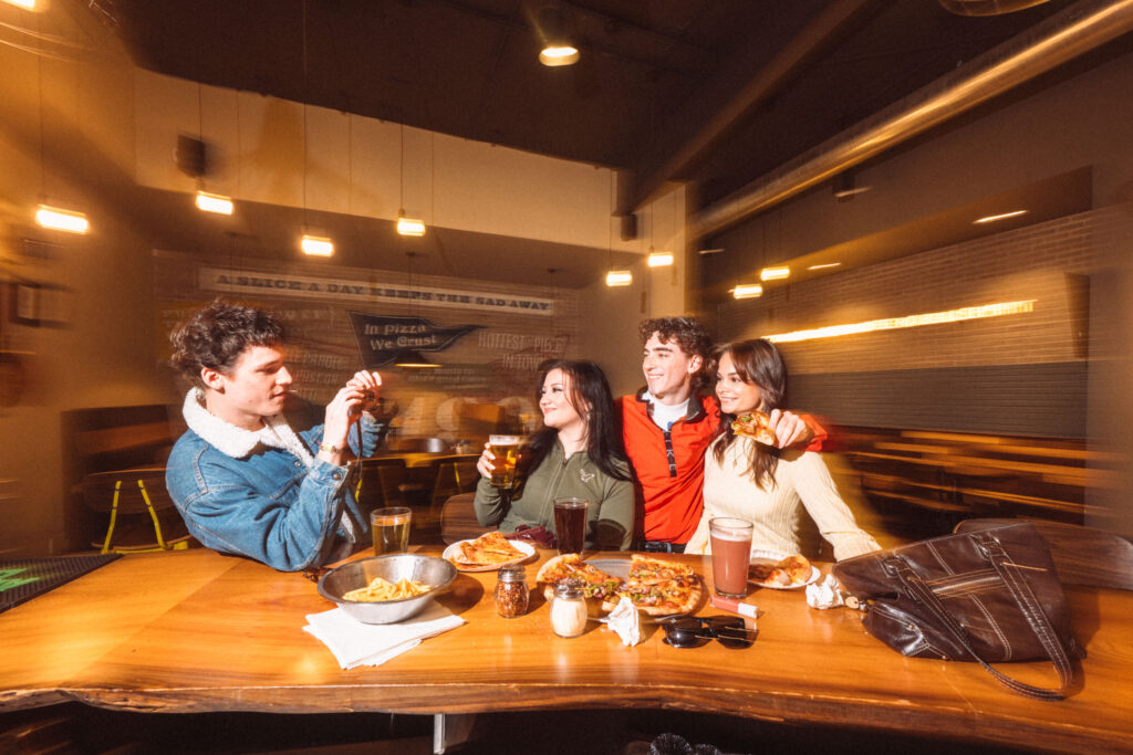 Four people sit around a wooden table at Rotolo’s, smiling and posing for a photo, celebrating 30 Years in a warmly lit restaurant.